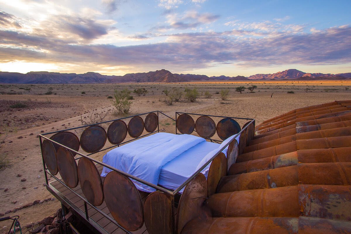 Camp Sossus Zeltzimmer mit Bett auf dem Dach bei Dämmerung