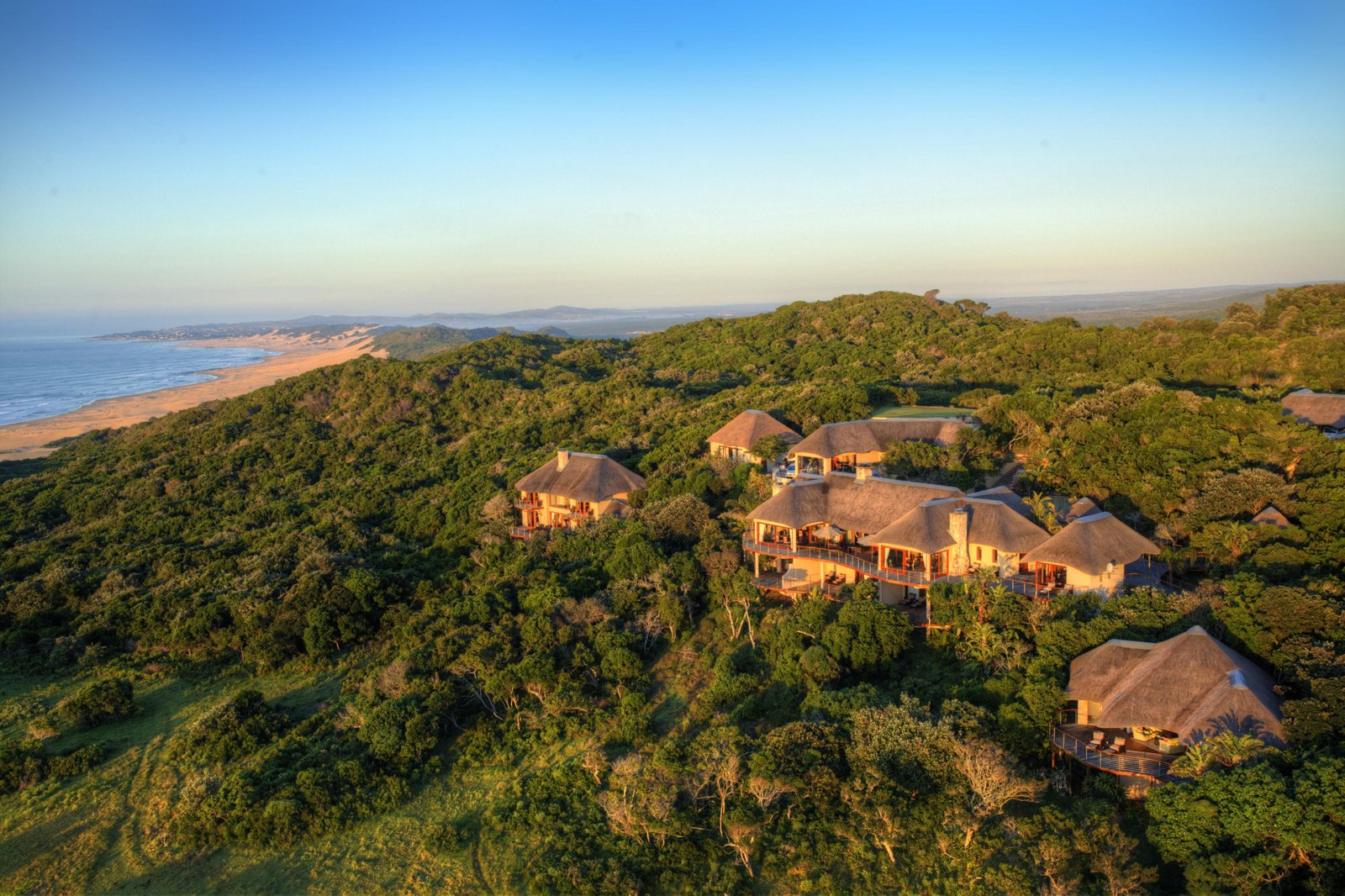 Lodge von Oben mit umliegenden Bäumen, Strand und Meer