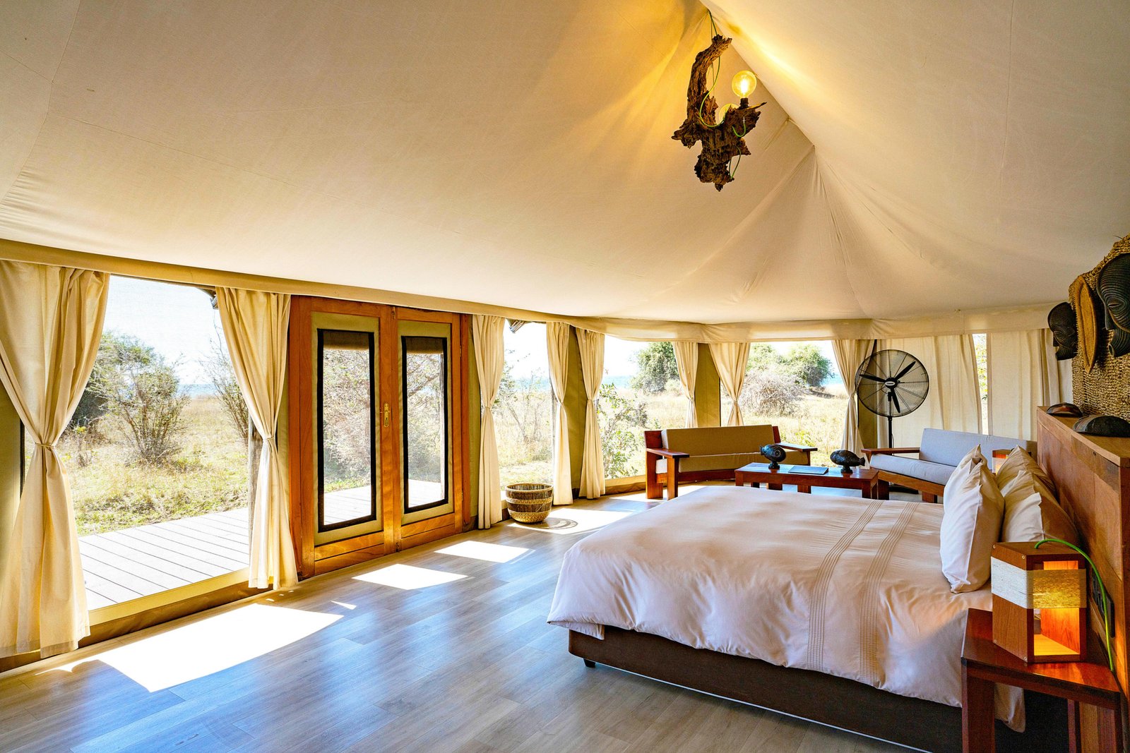 Zeltzimmer der Konkamoya Lodge mit gemütlichem Bett, kleinem Wohnbereich mit Sofas und Blick auf die Terrasse sowie ins Grüne