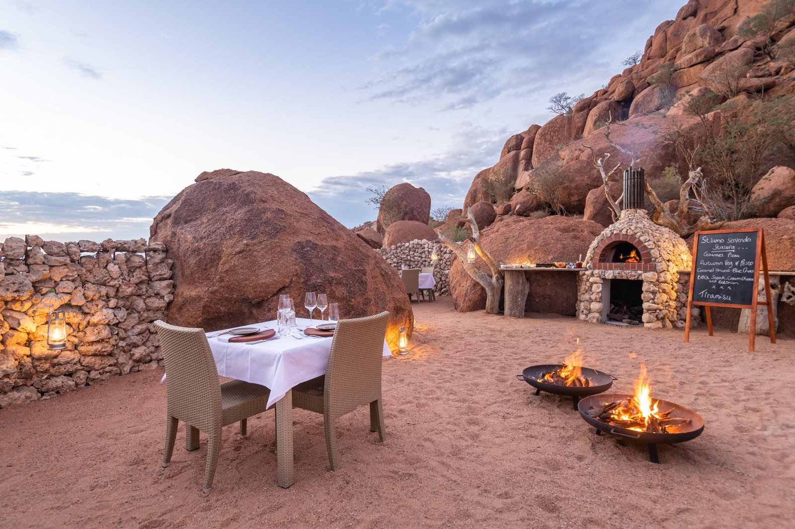 Dining Area zwischen Felsen mit Feuerschalen und Pizzaofen
