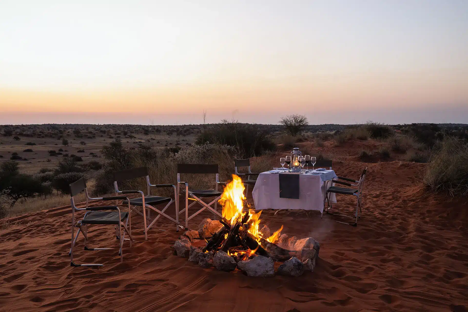 Gedeckter Tisch in der Kalahari mit Feuerstelle und Stühlen rundum