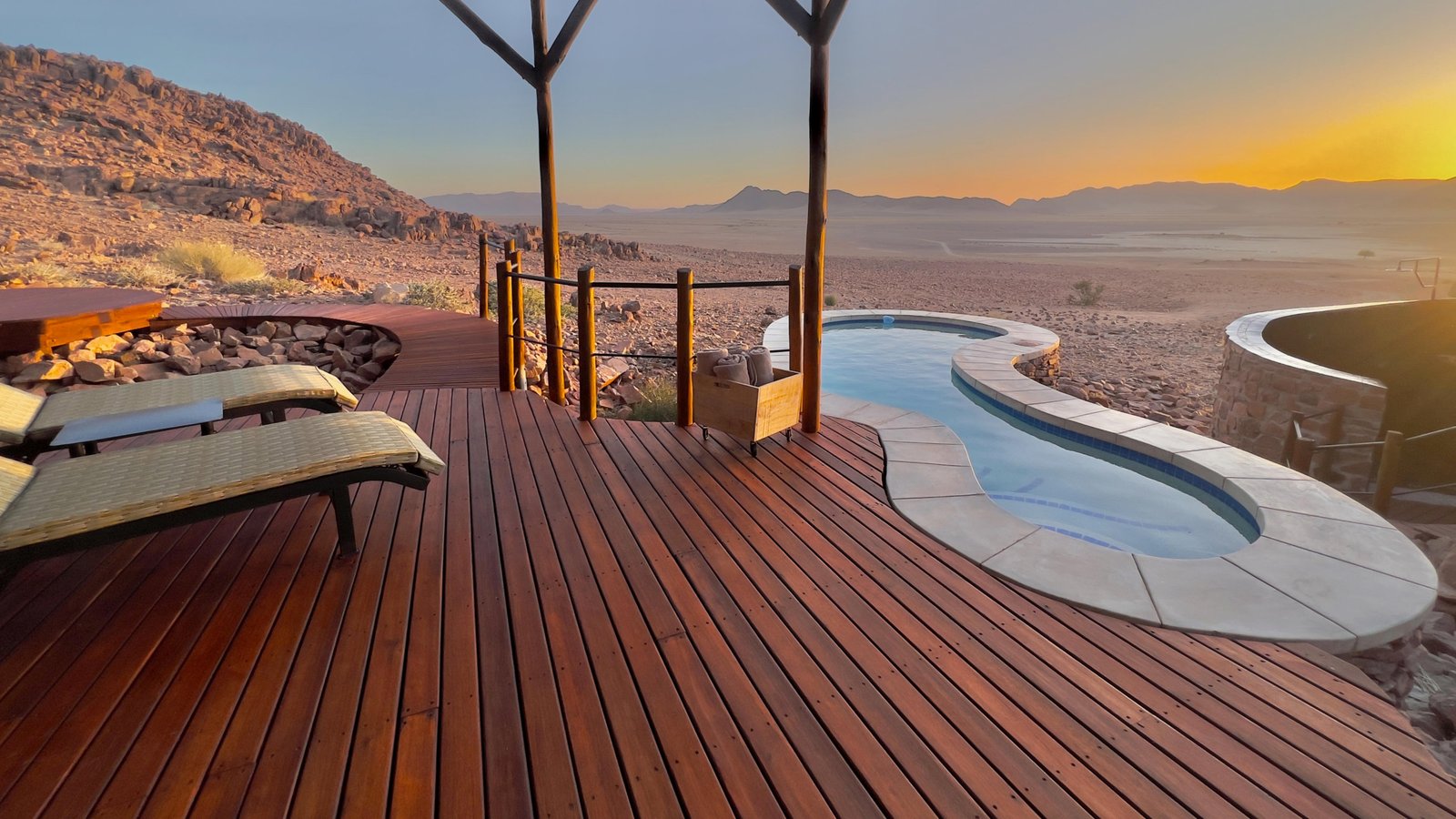 Terrasse mit Liegestühlen und Pool mit Blick in die Wüste