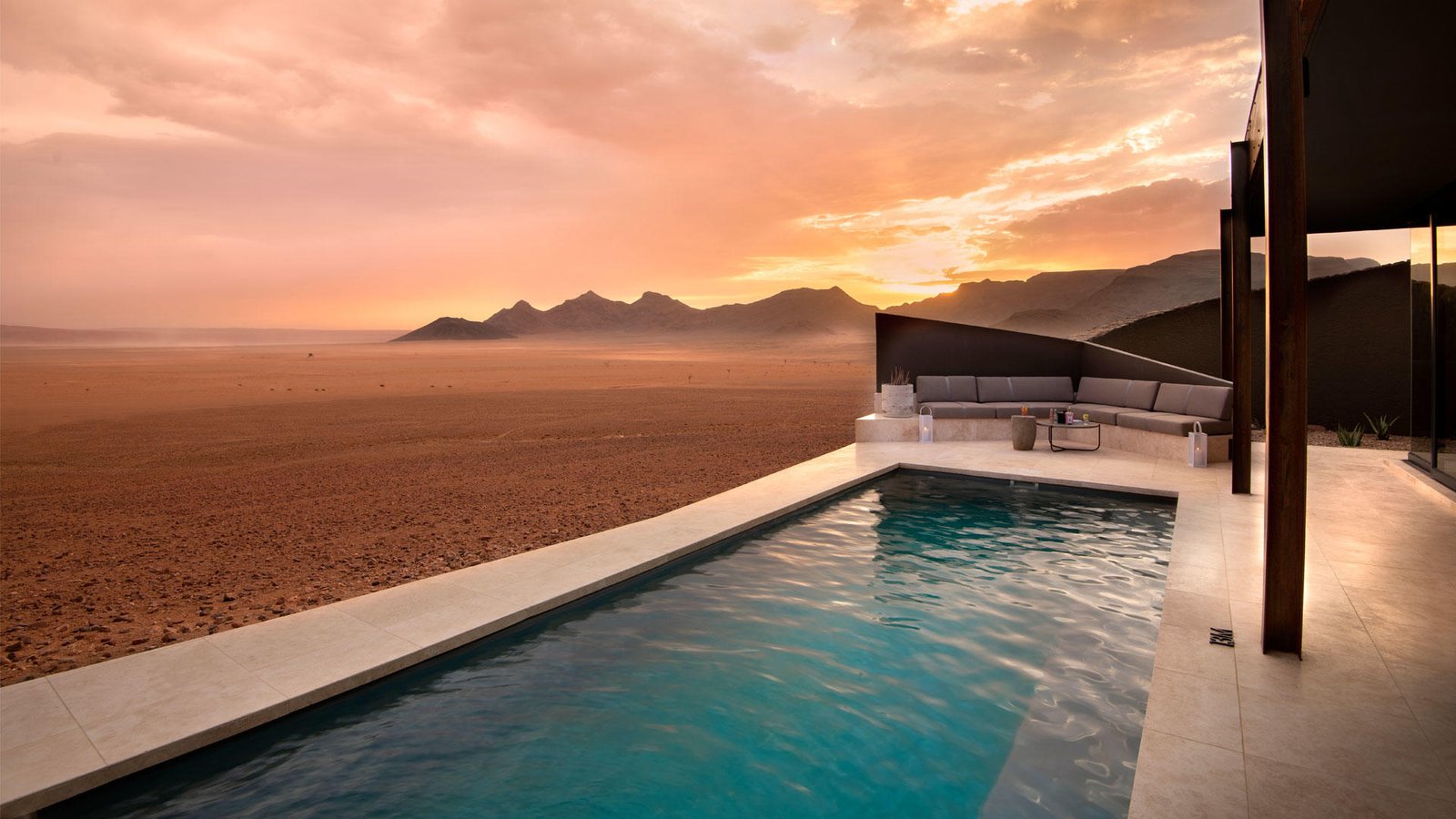 Swimmingpool mit Loungebereich und Blick auf die Wüstenlandschaft bei Sonnenuntergang