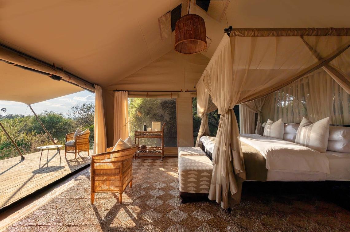 Zeltzimmer mit komfortablem Bett, privater Terrasse und Blick in den Busch