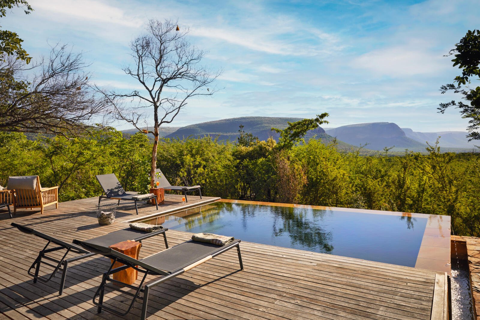 Swimmingpool mit Liegestühlen und Blick auf die umliegende Natur