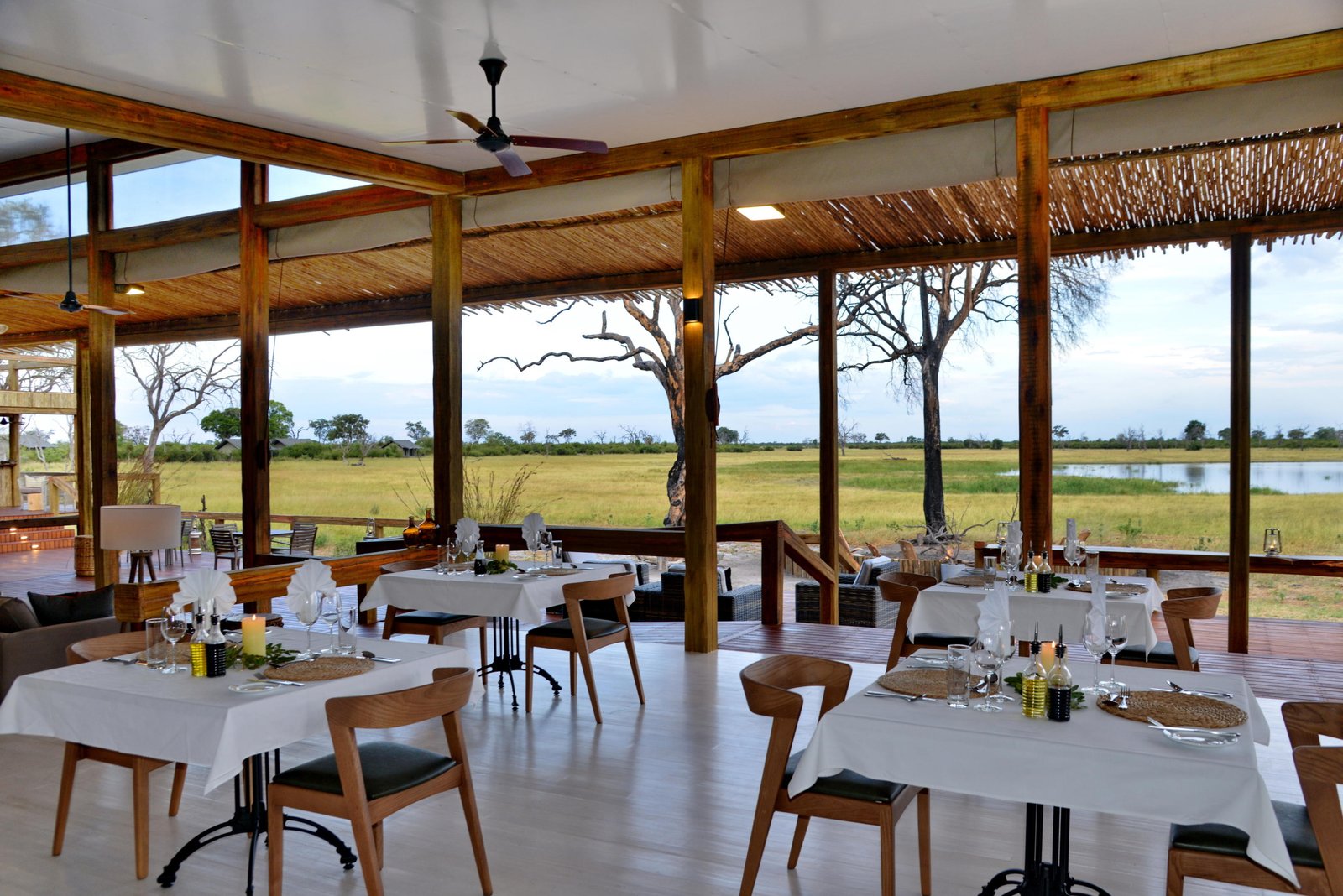Gedeckte Tische im Restaurantbereich der Lodge mit Blick auf das Wasserloch
