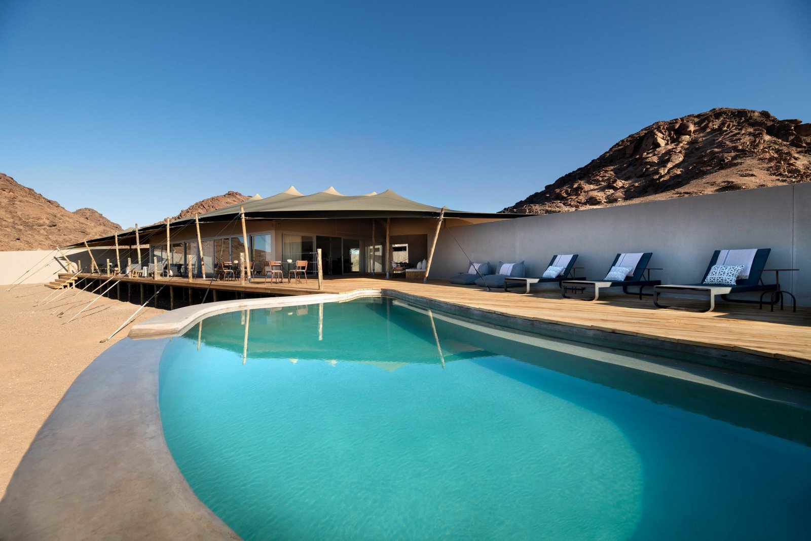 Swimmingpool mit Liegestühlen im Hauptbereich der Lodge