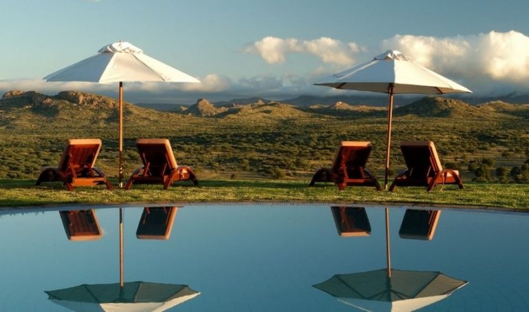 Swimmingpool mit Liegestühlen und Blick auf die weite Landschaft