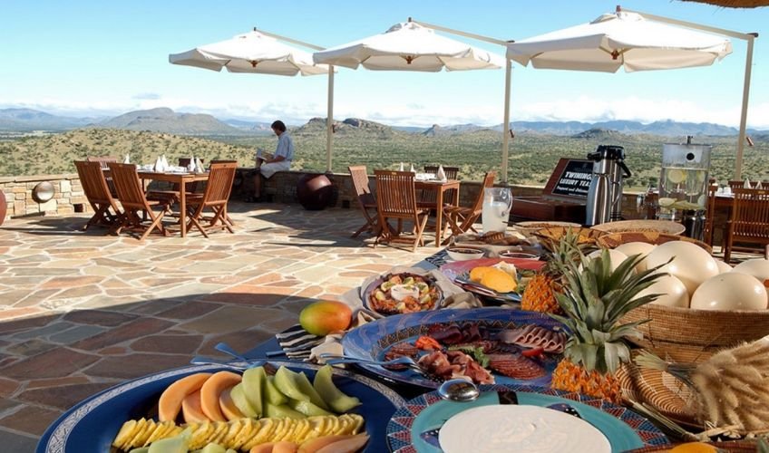 Terrasse mit gedeckten Tischen, Buffet mit verschiedenen Speisen und Blick auf die umliegende Natur